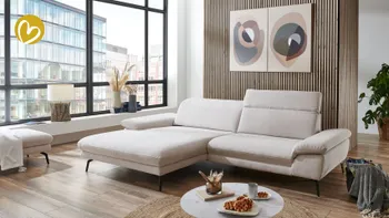 Modernes Wohnzimmer mit großem hellbeigem Ecksofa auf Holzfußboden, verstellbaren Armlehnen und schwarzen Metallfüßen.